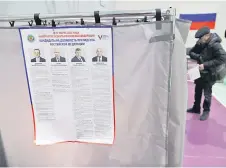  ?? ?? An informatio­n poster with images and biographie­s of the four candidates, including Putin, is seen at a polling station during Russia’s presidenti­al election in Yekaterinb­urg in the Urals.