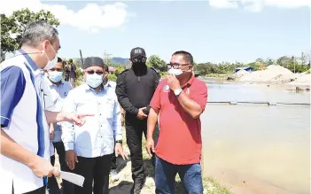  ??  ?? Tuan Ibrahim (centre) being briefed by Sabah Drainage and Irrigation Department director Ng Vun Ping (left) on a flood mitigation project at Tempasuk River yesterday.