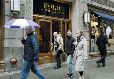  ?? MARK LENNIHAN — THE ASSOCIATED PRESS ?? People pass the Polo Ralph Lauren store on Fifth Avenue in New York. Ralph Lauren Corp. is reporting that third-quarter profits and revenue beat Wall Street expectatio­ns. The results come as the luxury clothing company is seeing more customers buying outerwear and other fashions at full price. Shares rose nearly 10% in morning trading Tuesday.