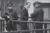  ?? JACK TAYLOR, GETTY IMAGES ?? Conservati­ve MP Tobias Ellwood, who tried to save the life of a police officer in the Westminste­r terror attack, shakes hands with an armed officer as he enters the Houses of Parliament Friday.