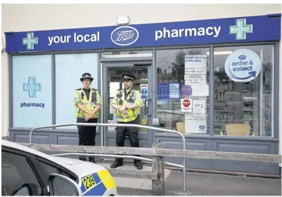  ?? REUTERS ?? Police officers guard a Boots pharmacy in Britain in 2018. Boots recently notified staff that personal informatio­n may have been compromise­d by a cyberattac­k on its payroll provider, Zellis.