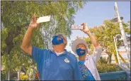  ??  ?? Allan Ansdell Sr. and wife Yvonne, parents of Allan Ansdell Jr, owner and president of Adventure City, use their smartphone­s to record their great-grandchild­ren riding a roller coaster at the amusement park.