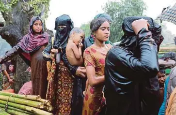  ??  ?? WANITA Rohingya beratur ketika hujan untuk menerima bantuan makanan di kem pelarian Kutupalong di Ukhiya, Coxs Bazar, Bangladesh kelmarin. - EPA