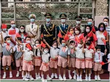  ?? ?? Primary school children and their parents pose for a photo with People’s Liberation Army soldiers during a morning flagraisin­g assembly, part of what has been dubbed ‘‘a unique approach to national education’’.