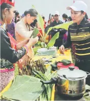  ??  ?? Young historians tried their hand at wrapping ‘kuih bongkol’.