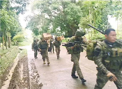  ?? AP FOTO ?? REINFORCEM­ENT. Additional troops carry supplies as they arrive at their barracks in the outskirts of Marawi City, Lanao del Sur to reinforce fellow troops following the siege by Muslim militants.