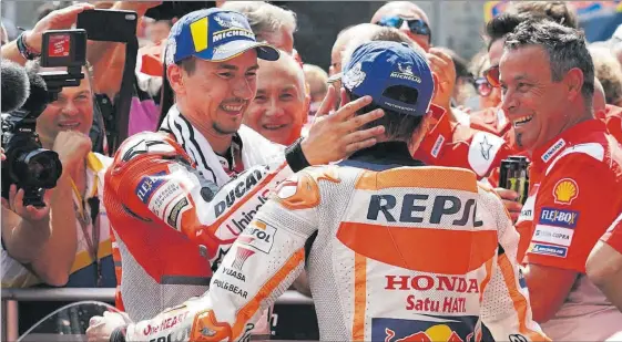  ?? ALEJANDRO CERESUELA ?? Jorge Lorenzo i Marc Márquez es feliciten davant de la mirada de Juanito Llança, mecànic de confiança del mallorquí, al ‘corralito’ de Spielberg.