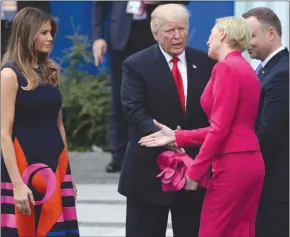  ??  ?? Poland’s first lady, Agata Kornhauser-Duda, reaches out to U.S. first lady Melania Trump as President Donald Trump offers his hand for a handshake after his speech in Krasinski Square, Warsaw, Thursday. Right, is Polish President Andrzej Duda.