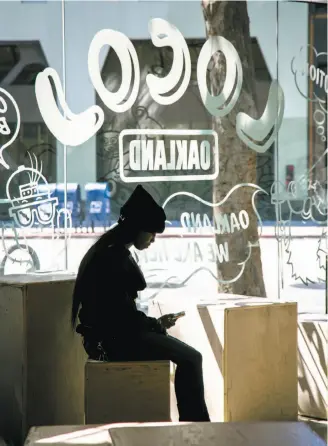  ?? John Storey / Special to The Chronicle ?? A woman checks her phone at Locol’s Uptown Oakland location, which closed this month.