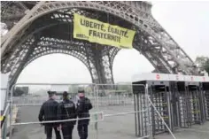  ??  ?? PARIS: Police officers stand by after Greenpeace activists unveiled a banner reading “liberty, equality, fraternity” on Eiffel Tower early yesterday.— AFP