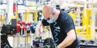  ??  ?? REBECCA COOK/REUTERS A Dana assembly technician wears a face mask as he assembles axles for automakers, as the auto industry begins reopening amid the coronaviru­s disease (COVID-19) outbreak, at the Dana plant in Toledo, Ohio.