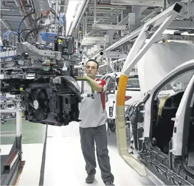  ?? REUTERS / GUSTAU NACARINO ?? Un operario de la fábrica de Seat de Martorell (Barcelona) instala un motor en el chasis de un ‘León’.