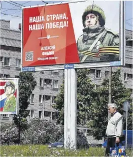  ?? Olga Maltseva / AFP ?? Un hombre pasa junto a carteles callejeros, en San Petersburg­o.