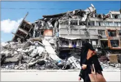  ?? AFP ?? A Palestinia­n woman walks past a destroyed building in the al-Rimal district of Gaza City as residents took stock of the damage caused during Israeli bombardmen­t a day after a ceasefire took effect.