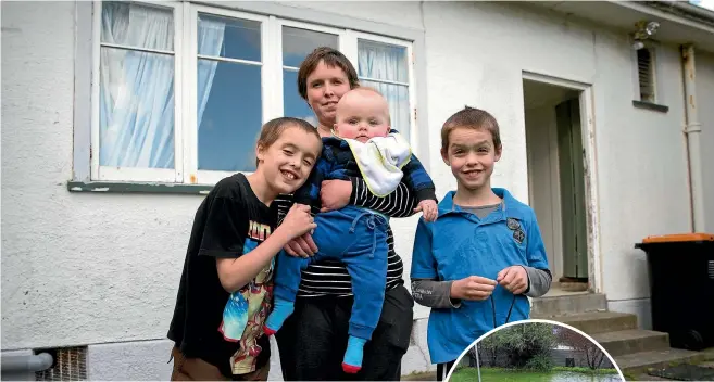  ?? PHOTO: MURRAY WILSON/FAIRFAX NZ ?? Jillian Sinclair is looking for a new home after a pool of water was discovered under her rental property. From left Kaleb Beaven, 10, Jillian Sinclair, holding Hayden Mckinley, 1 and Ethan Beaven, 9. The backyard in 2015.