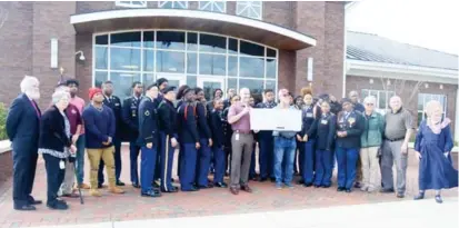  ?? (Photo by Charlie Benton, SDN) ?? Flanked by West Point High School JROTC cadets and other supporters, David Sawtelle, left, and MSU G.V. “Sonny” Montgomery Center for America’s Veterans Director Brian Locke hold a check for $3,500 raised for the center by citizens of West Point. The check was presented to the center in a ceremony Thursday.