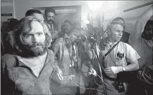  ?? Bettmann Archive/Getty Images ?? CHARLES MANSON is led into jail before a throng of news media. Reporter Linda Deutsch said the scene was “crazy ... and I didn’t know how crazy it was going to be for the entire trial.”