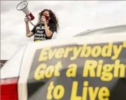  ?? Alexandra Wimley/Post-Gazette ?? A community organizer for the Thomas Merton Center, stands on a car and uses a megaphone to address attendees before a car and bike caravan to speak out against state violence, racism, and poverty, June 14, 2020, in the Hill District.