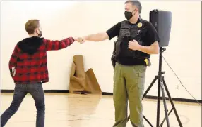  ?? Westside Eagle Observer/MIKE ECKELS ?? A sixth-grade student receives a fist bump from Decatur Police Chief Steve Grizzle during a book presentati­on ceremony at Decatur Middle School on Friday morning. Grizzle and the project sponsors handed out the book, “Be The Best You Can Be,” to help young people cope with everyday life situations.