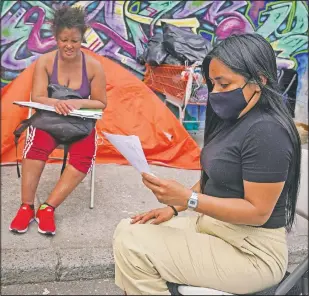  ??  ?? Yessenia Benitez (right), a 30-year-old licensed clinical social worker, tries to help a homeless woman sort through some documents near a homeless encampment in the Queens borough of New York.