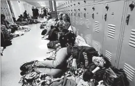  ?? GERALD HERBERT/AP ?? Emily Hindle makes do at a shelter set up at Rutherford High in Panama City Beach, Fla.