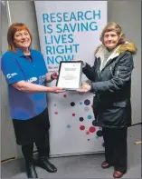  ?? ?? Cancer Research UK’s relationsh­ip manager Lynn Stewart hands over a long service award to June Pearson after 55 years’ service.