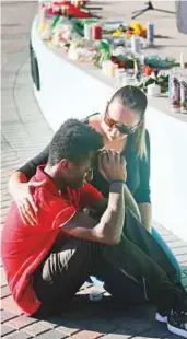  ?? AP ?? A girl comforts a student as they light a candle at a memorial for victims of Marjory Stoneman Douglas High School shooting.