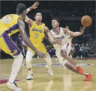  ?? Kelvin Kuo Associated Press ?? EITHER Clippers guard Tyrone Wallace is making a very fancy no-look pass or he is simply losing the handle as he’s guarded by Julius Randle, left, and Jordan Clarkson. Wallace scored 23 points.