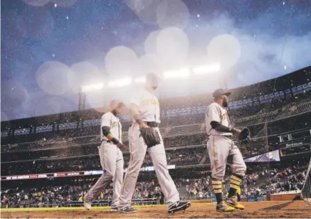  ??  ?? From right, Josh Harrison, Gregory Polanco and Starling Marte of the Pittsburgh Pirates walk off the field as rain drenches Coors Field, delaying the series opener against the Rockies on Monday night. Photos by AAron Ontiveroz, The Denver Post