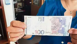  ??  ?? Not real: A businesswo­men showing a fake RM100 note.