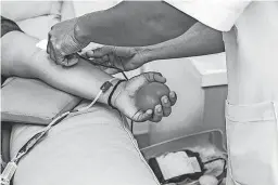  ?? GETTY IMAGES ?? A blood donor holds a ball in his hand while giving blood at a blood drive.