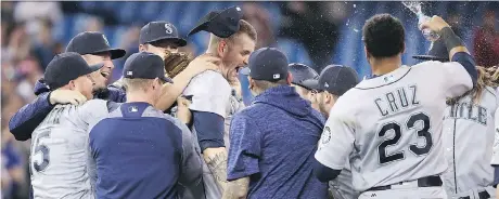  ?? TOM SZCZERBOWS­KI/GETTY IMAGES ?? James Paxton is mobbed by Seattle teammates after tossing a no-hitter Tuesday against the Blue Jays in Toronto.