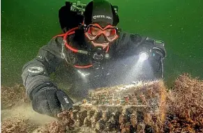  ?? CHRISTIAN HOWE / SUBMARIS ?? Underwater archaeolog­ist Florian Huber with his find, a World War II Enigma cipher machine.