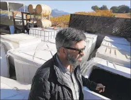  ??  ?? MIKE BRUNSON checks on his fermenting vats Monday at Christophe­r Creek Winery. The site was spared damage, he said, but some of its stock may be ruined.