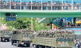  ?? Photo: REUTERS ?? ‘Nothing to see here’: Paramilita­ry policemen ride on trucks during a parade in central Urumqi, in a show of strength following a terrorist attack.