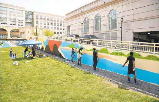  ?? PAUL W. GILLESPIE/CAPITAL GAZETTE PHOTOS ?? Artist Comacell Brown and volunteers paint a mural to memorializ­e Carr’s Beach, a historical landmark in the Annapolis Black community at The Maryland Cultural and Conference Center StageOne at Park Place Saturday.