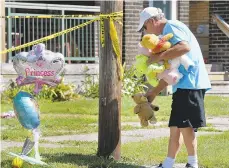  ?? GREG WOHLFORD/ERIE TIMES-NEWS VIA AP ?? Paul Laughlin, 57, places stuffed animals Sunday outside a home at 1248 W. 11th St. in Erie, where multiple children died in an early morning fire.