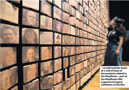  ??  ?? A staff member looks at a wall of faces of descendant­s related to the Mayflower – part of the Mayflower 400: Legend and Legacy exhibition at The Box