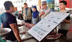  ?? PIC BY POLIANA RONNIE SIDOM ?? Sabah Fisheries Department marine resource management assistant director Lawrence Kissol (second from right) at an awareness programme at a market in Sandakan yesterday.