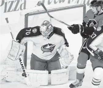  ??  ?? Columbus Blue Jackets goalie Joonas Korpisalo makes a save as Calgary Flames’ Joe Colborne looks for a rebound during the first period in Calgary on Friday.