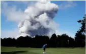  ?? JAE C. HONG / AP ?? Doug Ralston plays golf in Hawaii as a huge ash plume rises from the summit of Kilauea volcano on Monday.