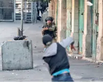  ?? ?? A PALESTINIA­N HURLS STONES at a member of Israeli security forces amid clashes in the West Bank city of Hebron on November 4.