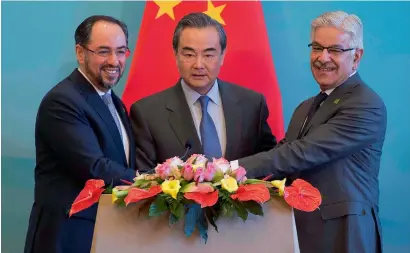  ?? AFP ?? Afghanista­n’s Foreign Minister Salahuddin Rabbani, China’s Foreign Minister Wang Yi and Pakistan’s Foreign Minister Khawaja Asif join hands at the end of their joint Press conference after the first China-Afghanista­n-Pakistan Foreign Ministers’ Dialogue in Beijing on Tuesday. —