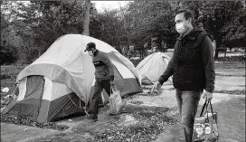  ?? COURTESY OF TORRANCE PATRICK ?? Torrance Patrick (left) and Alva Jones prepare to hand out sandwiches at a homeless encampment in metro Atlanta.