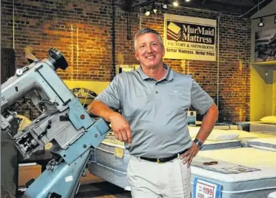  ?? CONTRIBUTE­D PHOTO ?? MurMaid Mattress owner Roger Pickett stands with the original sewing machine that the company started with in 1979.