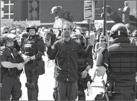  ?? AP/The Charlotte Observer/JEFF SINER ?? A man live streams video as he is detained by police outside Bank of America Stadium, where people were protesting Sunday in Charlotte, N.C.