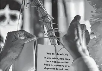  ?? ?? A woman ties a ribbon on the Circle of Life wooden hoop in memory of a loved one Thursday. The hoop is part of MECA’s ofrenda exhibition.