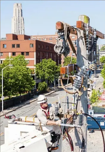  ?? Andrew Rush/ Post- Gazette ?? Mike Joyce, a journeyman undergroun­d splicer with Duquesne Light, works on a utility poll on May 15, in Oakland. When the Pennsylvan­ia Public Utility Commission ordered the large public utilities that it governs to stop shutting off non- paying customers because of the COVID- 19 pandemic in mid- March, the vast majority of municipal utilities followed suit