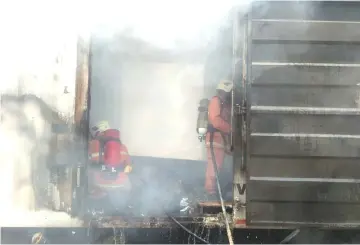  ??  ?? Firemen putting out the fire inside the cargo section of the truck.