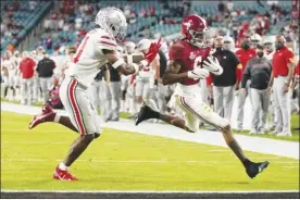  ??  ?? Alabama wide receiver DeVonta Smith scores a touchdown past Ohio State safety Josh Proctor during the first half Monday.